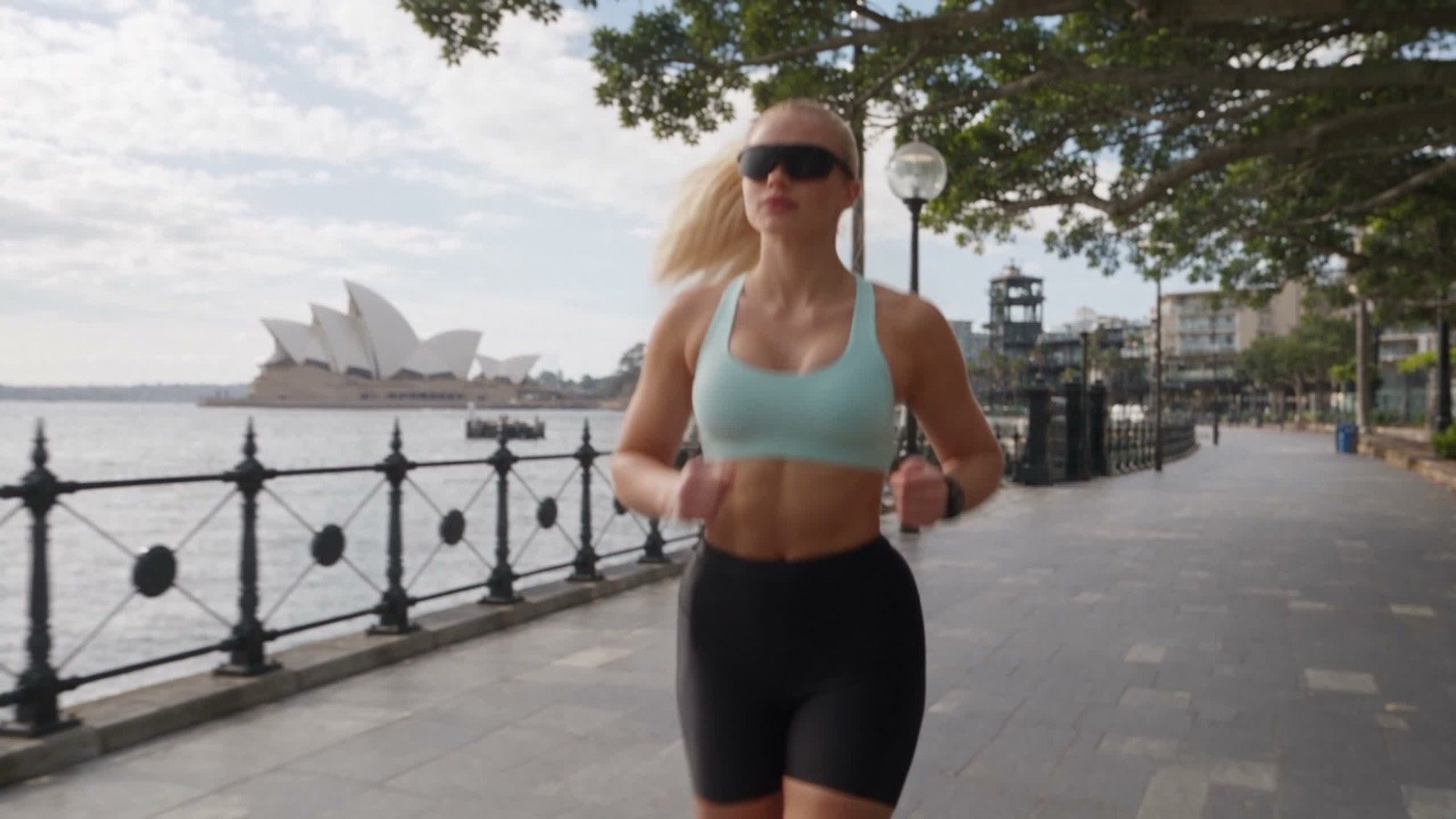 Runner wearing smart sunglasses on a harbour promenade — Elnuvi spec film