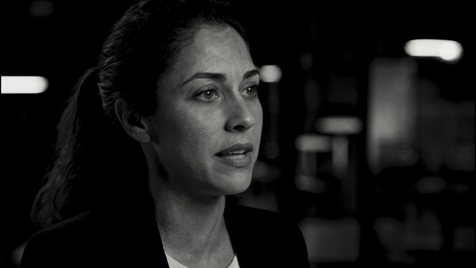 Woman in a dark office, black-and-white frame from an app launch trailer